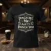 Pinch Me Me And I'll Punch You text design on a black t-shirt with ornate border and fist graphics