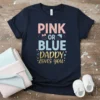 Navy blue t-shirt with "PINK OR BLUE DADDY LOVES YOU" text in pink, blue, and gold glitter font, featuring baby