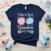 Navy t-shirt with "Pink or Blue Grandma Loves You" text, featuring pink and blue floral graphics and baby footprints