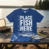 Blue t-shirt with white text "Place Fish Here" and a bass fish graphic, featuring a measuring scale on the left