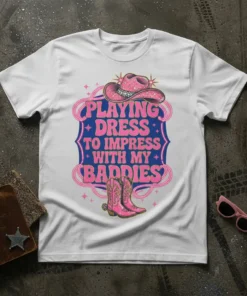 White t-shirt with pink and blue text reading "Playing Dress to Impress With My Baddies" and featuring a pink cowboy
