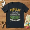 POPULAR HERE TO HELP YOU GET INTO MISCHIEF YOU HAVEN'T THOUGHT OF YET quote on a dark t-shirt with yellow