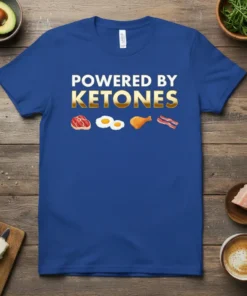 Blue t-shirt with white and gold text "POWERED BY KETONES" and graphics of steak, eggs, chicken leg, and bacon