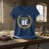 Blue t-shirt with "PRAISE BE" text inside a gold laurel wreath and sunburst graphic