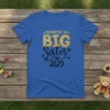 Promoted to BIG Sister 2025 text design with gold glitter and black script on a blue t-shirt, announcing sibling status