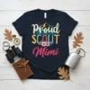 Proud SCOUT Mimi t-shirt design with mountains, trees, and floral accents. Features the text "Proud SCOUT Mimi" in colorful lettering