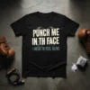 Black t-shirt with bold white text "PUNCH ME IN TH FACE" and smaller blue text "I NEED TO FEEL ALIVE"