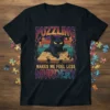 Black cat sitting on a puzzle box with the text "PUZZLING MAKES ME FEEL LESS MURDERY" on a t-shirt