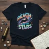 Black cat jumping through a colorful galaxy with the words "REACH FOR THE STARS" above it, on a t-shirt