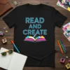 Black t-shirt with bold turquoise and pink text reading "READ AND CREATE" above an open book graphic