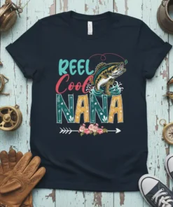 REEL Cool NANA text with a jumping bass fish graphic and floral accents on a navy t-shirt