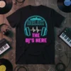Black t-shirt with "RELAX THE DJ'S HERE" text in neon blue and pink, featuring headphones and a sound wave graphic