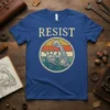Vintage Resist t-shirt design featuring a flexing arm with growing plants inside a circular emblem, "RESIST" text above