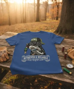 Black retriever wearing a "HUNT" hat and holding a duck, with "RETRIEVER & RELIABLE" text below, on a blue t-shirt