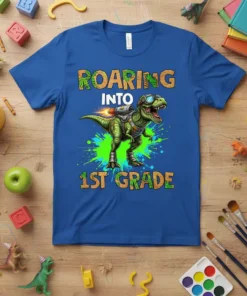 Roaring Into 1st Grade T-Shirt with a green T-Rex dinosaur wearing goggles and a jetpack, printed on a blue shirt