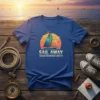 Sail Away Ocean Adventure Awaits text with a sailboat graphic on a blue t-shirt, depicting a sunset over the ocean