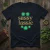 Sassy lassie text in gold glitter font with green glowing shamrocks on a navy t-shirt for St. Patrick's Day
