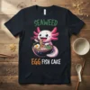 Cute axolotl eating ramen with text "SEAWEED EGG FISH CAKE" on a black t-shirt