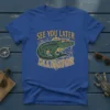 See You Later Alligator text with a cool alligator wearing rainbow sunglasses on a blue t-shirt