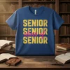 Blue t-shirt with "SENIOR SENIOR class of SENIOR" text in yellow and pink, perfect for graduation