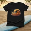 Black t-shirt featuring the word SHAKA inside a stylized ocean wave graphic with palm trees