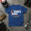 Blue t-shirt with "SHAKE & BAKE 24'" and "IF YOU'RE NOT 1ST, YOU'RE LAST" text in white and yellow, inspired