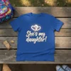 Blue t-shirt with "She's my daughter!" text and glowing heart graphic, perfect for proud parents