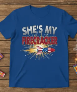 She's My Firecracker patriotic couple t-shirt design with a rocket blasting fireworks, featuring bold typography