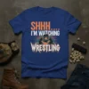 SHHH.... I'M WATCHING WRESTLING text with graphic of two wrestlers grappling on a blue t-shirt