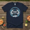 Navy blue t-shirt with "Shrimp Life" text, two shrimp graphics, aviator sunglasses, and blue wave design in a circle