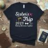 Sisters Trip 2025 Making Memories Together text with champagne glasses and airplane graphic on a navy t-shirt