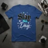 Blue t-shirt with "Slay ALL Day" text in gothic and neon fonts, surrounded by colorful stars
