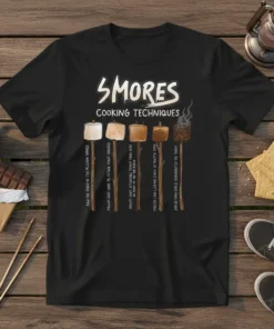 Black t-shirt displaying "Smores Cooking Techniques" with illustrations of marshmallows in different stages of roasting, each with a humorous caption