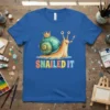 SNAILED IT text with a cute snail wearing a crown and holding a paintbrush on a blue t-shirt