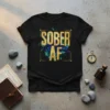 Sober AF text design with gold glitter and abstract colorful splatter on a black t-shirt
