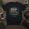 Black t-shirt with "SOCIAL MEDIA MANAGER Like a normal manager, only way cooler." text in gold and white, framed by