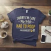 Navy blue t-shirt with "SORRY I'M LATE My Wife HAD TO POOP #HUSBANDLIFE" text in white and yellow, featuring a
