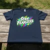Navy blue t-shirt with white "Stay Fearless" text surrounded by colorful spray paint and lightning bolt graphics