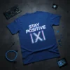 Stay Positive |X| t-shirt with a digital glitch effect on the text and symbol, presented on a blue shirt
