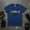 Navy blue t-shirt with "STRONG AF" text in gold, featuring muscular arms and barbed wire design