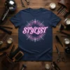 Navy blue t-shirt with the word "Stylist" in glowing pink neon text, surrounded by a circular design of combs and