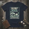 Surf Beach Adventure T-Shirt with shark and wave graphic, featuring palm trees and a sunset