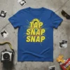 Blue t-shirt with yellow text "TAP SNAP SNAP" and a camera lens graphic, perfect for photographers