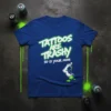 Blue t-shirt with neon green text reading "Tattoos ARE TRASHY SO IS YOUR MOM" and graphics of spray paint cans