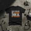 Black t-shirt with white and orange text: "TEACH YOUR KIDS TO CHANGE THEIR OIL NOT THEIR GENDER", featuring a wrench