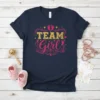 Team Girl text with gold glitter and pink script, decorated with baby feet and stars, on a navy t-shirt