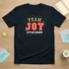 Team Joy Lifetime Member text in bold orange and yellow letters with a geometric frame on a dark navy t-shirt