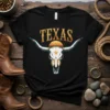 Black t-shirt featuring a stylized Texas Longhorn skull graphic with the word "TEXAS" above and a sunset graphic