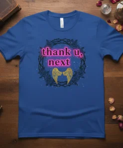 Blue t-shirt featuring the "thank u, next" text in neon pink, surrounded by a thorny rose wreath and golden angel