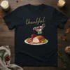 Navy t-shirt with the word "thankful" in gold script above a detailed illustration of a roasted turkey dinner with gravy